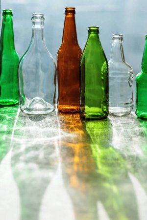 Leere Flaschen mit kreativen Schatten und fantastischen Highlights. Abfälle aus verschiedenen Glascontainern, die zum Recycling bereit stehen. Getrennte Sammlung von Glasmüll. Umweltfreundliches und abfallfreies Konzept