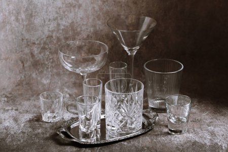 Téléchargez les photos : Collection de verres en cristal vides de différentes tailles et formes disposés élégamment sur une table texturée - en image libre de droit