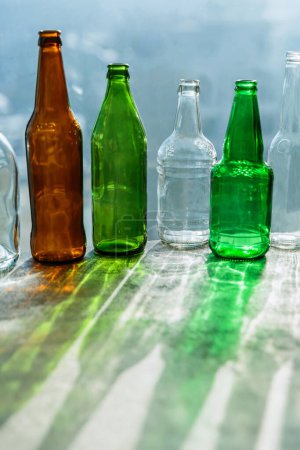 Leere Flaschen mit kreativen Schatten und fantastischen Highlights. Abfälle aus verschiedenen Glascontainern, die zum Recycling bereit stehen. Getrennte Sammlung von Glasmüll. Umweltfreundliches und abfallfreies Konzept