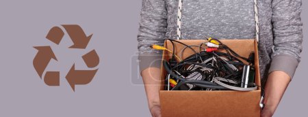 Des mains féminines méconnaissables tenant délicatement une boîte en carton remplie d'accessoires électroniques, favorisant un recyclage respectueux de l'environnement.
