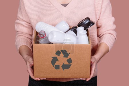 Frau hält mit Plastikmüll gefüllten Karton in der Hand und fördert damit das Umweltbewusstsein und verantwortungsvolle Entsorgungspraktiken.