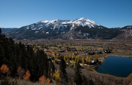 Aerial view of Crested Butte Town and properties with fall colors, a mountain background, and sunny blue skies