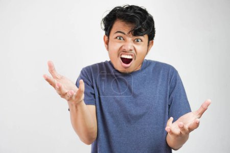 Foto de Guapo joven asiático con camiseta casual de pie sobre fondo blanco y gritando locamente y gritando con expresión agresiva y las manos levantadas. Concepto de frustración. - Imagen libre de derechos