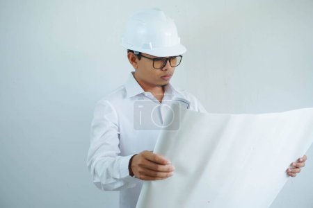 Téléchargez les photos : Jeune asiatique mâle architecte ingénieur sourire et tenant ingénierie plans isolés sur fond blanc. - en image libre de droit