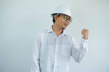 Téléchargez les photos : Jeune architecte asiatique homme portant le casque de sécurité constructeur sur fond isolé souriant avec le visage heureux regardant et pointant vers le côté avec le pouce vers le haut. - en image libre de droit