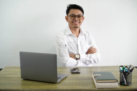 Foto de Joven asiático hombre de negocios en un lugar de trabajo con los brazos cruzados y mirando hacia adelante llevando camisa blanca aislada sobre fondo blanco - Imagen libre de derechos