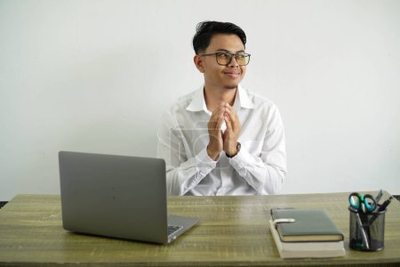 junger asiatischer Geschäftsmann an einem Arbeitsplatz intrigiert etwas, trägt weißes Hemd mit Brille isoliert