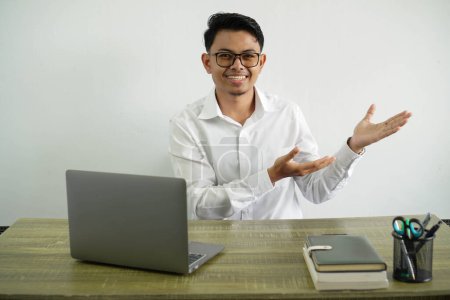 Foto de Joven asiático hombre de negocios en un lugar de trabajo extendiendo las manos a un lado para invitar a venir, usar camisa blanca con gafas aisladas - Imagen libre de derechos