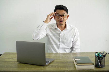 Photo for Young asian businessman in a workplace has just realized something and has intending the solution, wearing white shirt with glasses isolated - Royalty Free Image