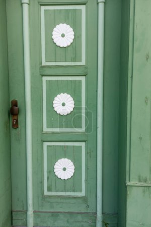 Photo for Old green wooden front door with large white flower blossoms framed in rectangles - Royalty Free Image