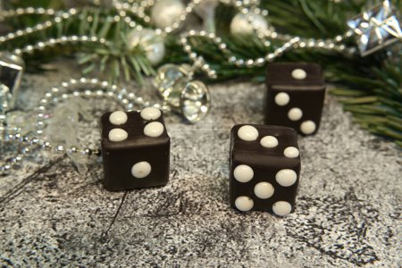 Dominoes with dots that look like dice in front of fir greenery and Christmas decorations