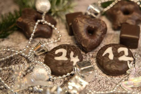 Chocolate cookies with the date of Christmas Eve in front of the Christmas decorations