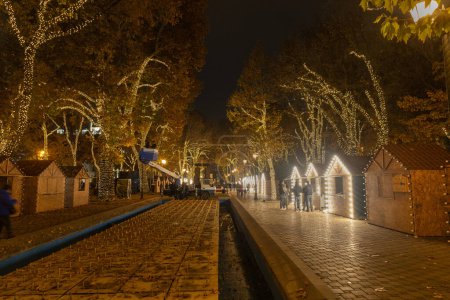 Téléchargez les photos : Erevan, Arménie - 3 décembre 2022 : Les travailleurs de la grue décorent les arbres et le marché de Noël pour Noël et le Nouvel An dans 2750 fontaines d'anniversaire, le soir. - en image libre de droit