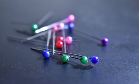A closeup picture of colourful ball pins spread over a black background.