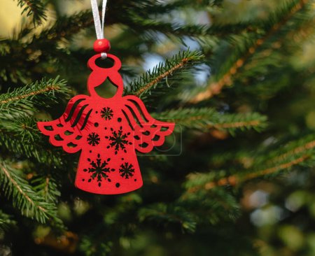 Ángel de Navidad escandinavo rojo colgando de un abeto. Decoración de Navidad de madera.