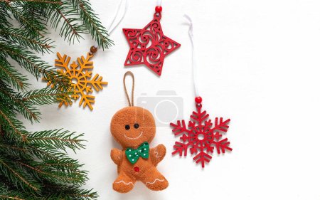 Photo for Christmas soft toy gingerbread man, wooden snowflakes and stars, fir tree branches on a white background. Copy space. - Royalty Free Image