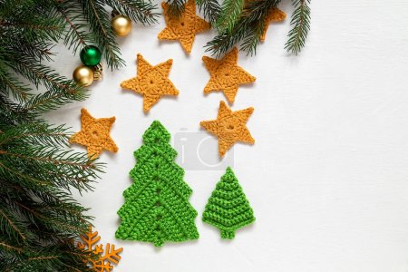 Festliche Weihnachtskomposition auf weißem Hintergrund. Handgestrickter grüner Weihnachtsbaum und gelbe Sterne. Kopierraum.