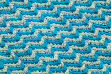 Foto de Knitted texture. Texture of jacquard fabric with white blue geometric pattern. Crochet mosaic pattern. - Imagen libre de derechos