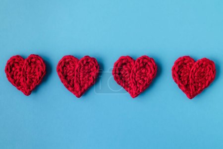 Foto de Four red crochet heart on a blue background. Happy Valentine's day concept. Top view. Copy space. - Imagen libre de derechos