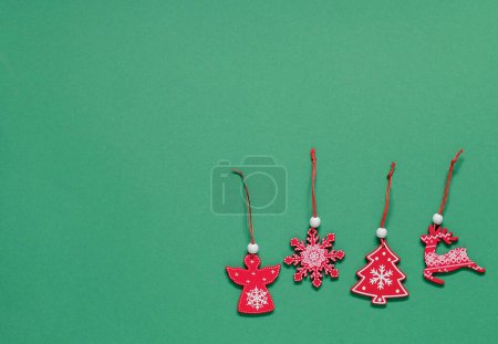 Téléchargez les photos : Jouets sapin de Noël en bois rouge sur un fond vert. Vue de dessus. Espace de copie. - en image libre de droit