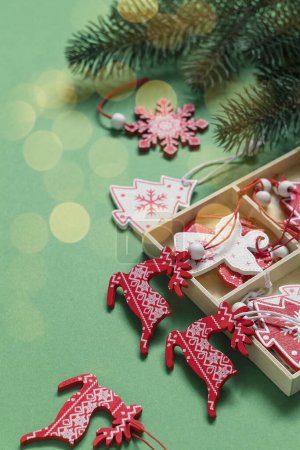 Téléchargez les photos : Boîte de Noël avec jouets en bois blanc rouge et branches de sapin sur fond vert. - en image libre de droit