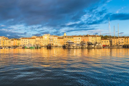 Foto de Vista panorámica de Saint Tropez reflejando al mar Mediterráneo en la luz dorada del atardecer contra el cielo dramático - Imagen libre de derechos