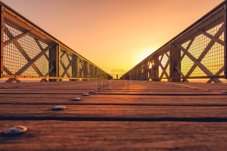 Foto de Vista panorámica de la cubierta de madera del puente convergiendo a la luz amarilla del atardecer en Biarritz Francia - Imagen libre de derechos