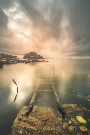 Téléchargez les photos : Vue panoramique d'une échelle en bois immergée dans la mer dans le sud de la France au coucher du soleil - en image libre de droit