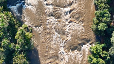 Aerial image of the apore river with brown water and riparian forest during the day