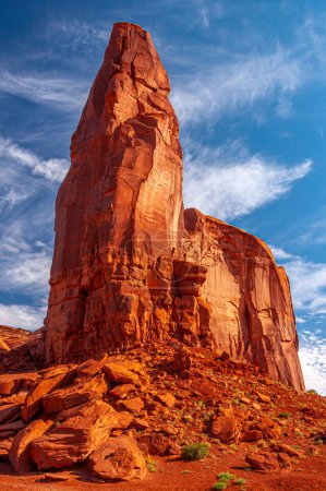 Téléchargez les photos : Une grande pierre monolithique se dresse au-dessus d'un ciel d'été bleu brillant avec des "ailes d'anges" dans Monument Valley, Arizona. - en image libre de droit