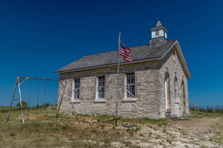Photo for A beautiful old historic schoolhouse with flag and playset still standing high on the Kansas prairie. - Royalty Free Image