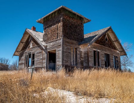 Téléchargez les photos : Cette maison abandonnée et négligée, ou peut-être une vieille école, se trouve abandonnée dans un village rural du nord-est du Nouveau-Mexique.. - en image libre de droit