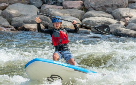 Photo for Canon City, Colorado - July 21, 2023: People enjoying the various events at the  Royal Gorge Whitewater Festival, a popular yearly event in Canon City. In this photograph, a SUP rider has just lost his balance in the whitewater. - Royalty Free Image