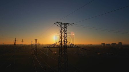 Strommast mit Strom. Energie- und Hochspannungsmast bei Sonnenuntergang oder goldener Stunde. Strombedarf und Stromausfallkonzept aufgrund von Elektrofahrzeugen oder Elektrofahrzeugen steigen. Netzinfrastruktur. 