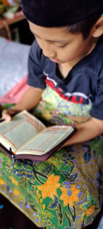 Téléchargez les photos : Magelang, Indonésie - 03 novembre 2022 : Portrait d'un garçon musulman lisant Al-Coran. - en image libre de droit