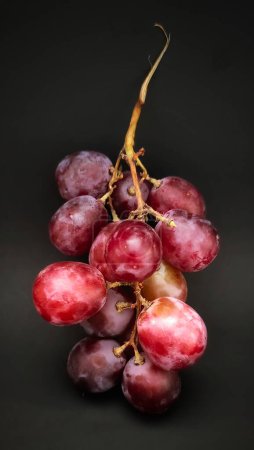 Photo for Photo of a bunch of red grapes against a plain black background - Royalty Free Image
