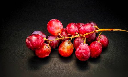 Foto de Foto de un racimo de uvas rojas sobre un fondo negro liso - Imagen libre de derechos