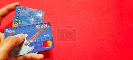 Photo for Central Java, Indonesia. January 29, 2023: Man holding cards isolated on red background - Royalty Free Image