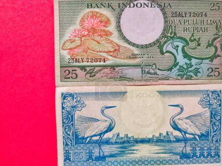 Foto de Vista de cerca de la moneda indonesia Rp25 rupias emitidas en 1959. Billetes de rupias aislados sobre fondo rojo. - Imagen libre de derechos