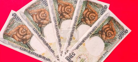 Foto de Vista superior de los antiguos billetes indonesios Rp.500,00 rupias emitidas en 1992. Antiguo concepto de moneda rupia aislado sobre fondo rojo. - Imagen libre de derechos