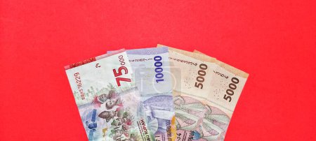 Téléchargez les photos : Vue de dessus des nouveaux billets émis en 2022. Roupie indonésienne monnaie isolée sur fond rouge - en image libre de droit