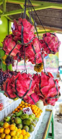 Foto de Varios racimos de fruta de dragón cuelgan en la tienda de frutas, también hay otras frutas. - Imagen libre de derechos