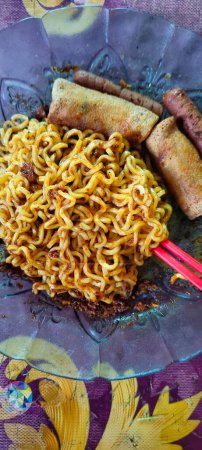 Photo for Portrait of typical Indonesian fried noodles complete with sausage and fried risol as a complement. - Royalty Free Image