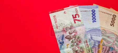 Téléchargez les photos : Espace négatif de nouveaux billets de banque en rupiah isolés sur un fond rouge - en image libre de droit