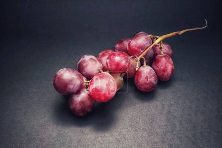 Foto de Se fotografió una ramita de uvas con el concepto de dar un efecto luminoso a las uvas aisladas sobre un fondo negro. - Imagen libre de derechos
