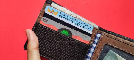 Téléchargez les photos : Le portefeuille de l'homme contient plusieurs cartes d'identité importantes isolées sur un fond rouge. - en image libre de droit