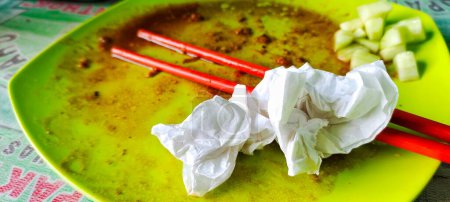 Photo for Close up view of a photo of the plate after eating, you can see several dirty tissue sheets and a pair of eating used chopsticks. - Royalty Free Image