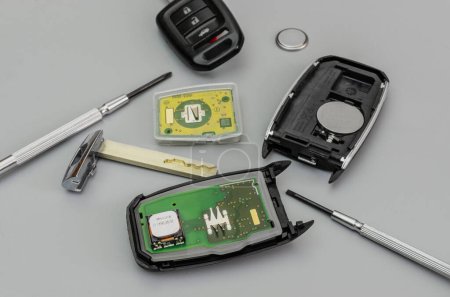 Kaputte oder beschädigte Autoschlüssel Fob und neue Remote-Fahrzeugschlüssel auf grauem Hintergrund. Reparatur von kaputten oder beschädigten Remote-Schlüsseln