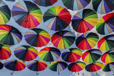 Foto de La imagen captura la vista de numerosos paraguas de colores suspendidos en el aire. Los paraguas son multicolores, cada uno con una combinación única de tonos. - Imagen libre de derechos