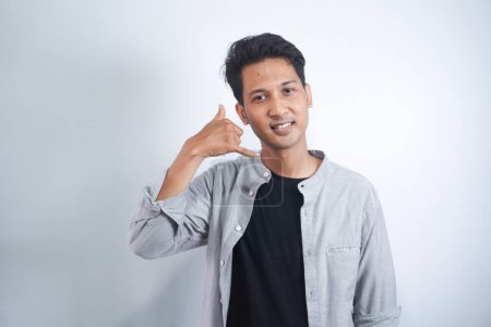 Photo for Young handsome Asian man over isolated background making phone gesture. Call me back sign - Royalty Free Image